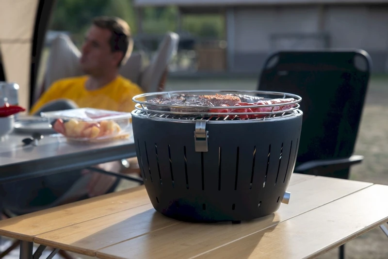 LotusGrill XL Hybrid houtskoolbarbecue - Rood LotusGrill XL Hybrid Houtskoolbarbecue - Rood -Buiten Kamperen Verkoop lotusgrill in gebruik met toppy shirtje 2